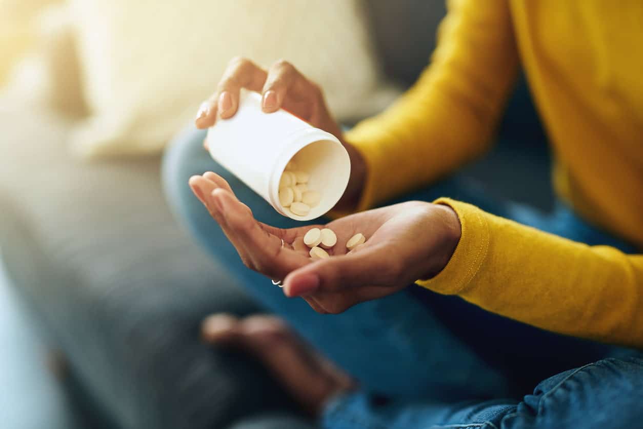 A women pouring out white circular tablets into her hand