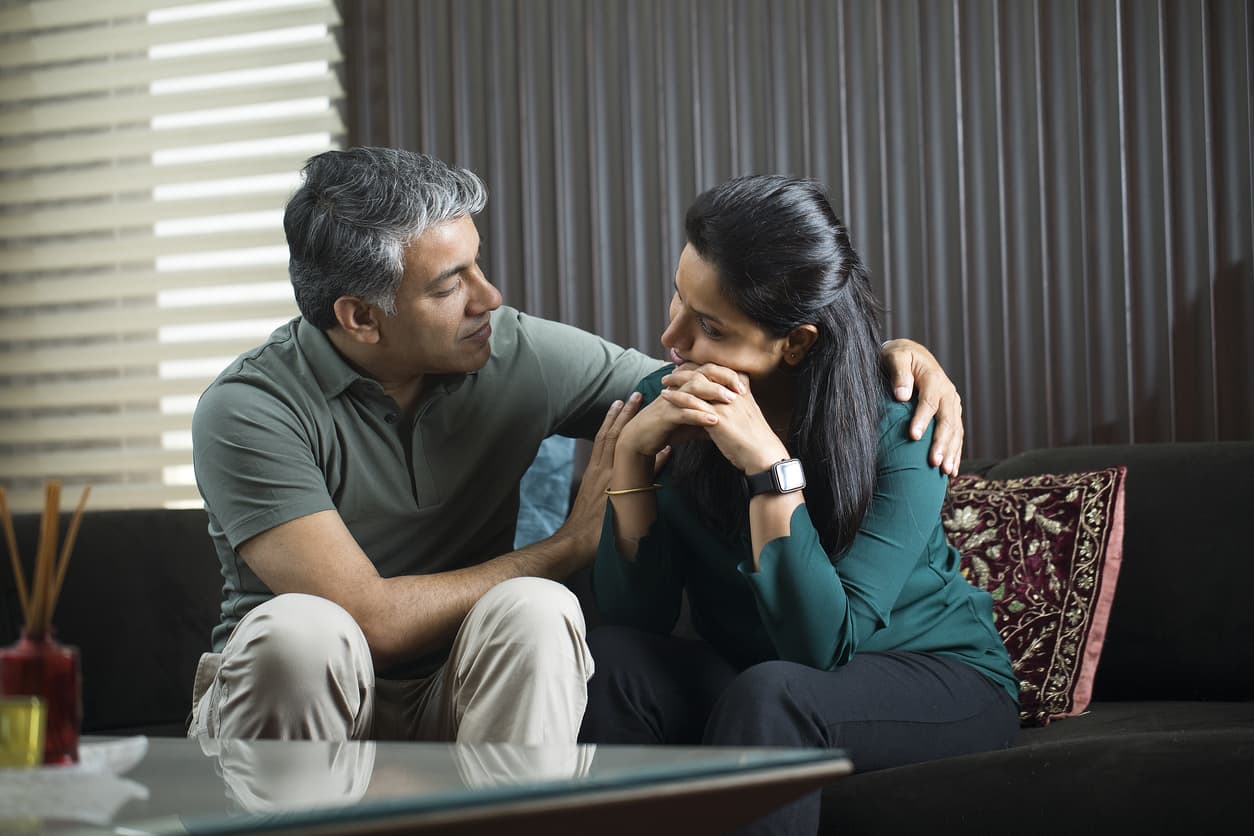 Female confiding in male who has his arm around her