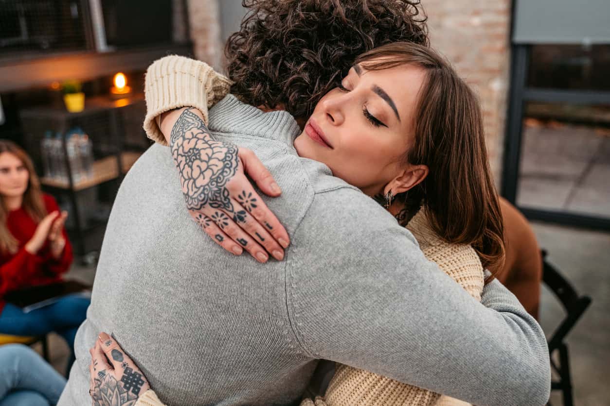 Man and women hugging at a rehab meeting